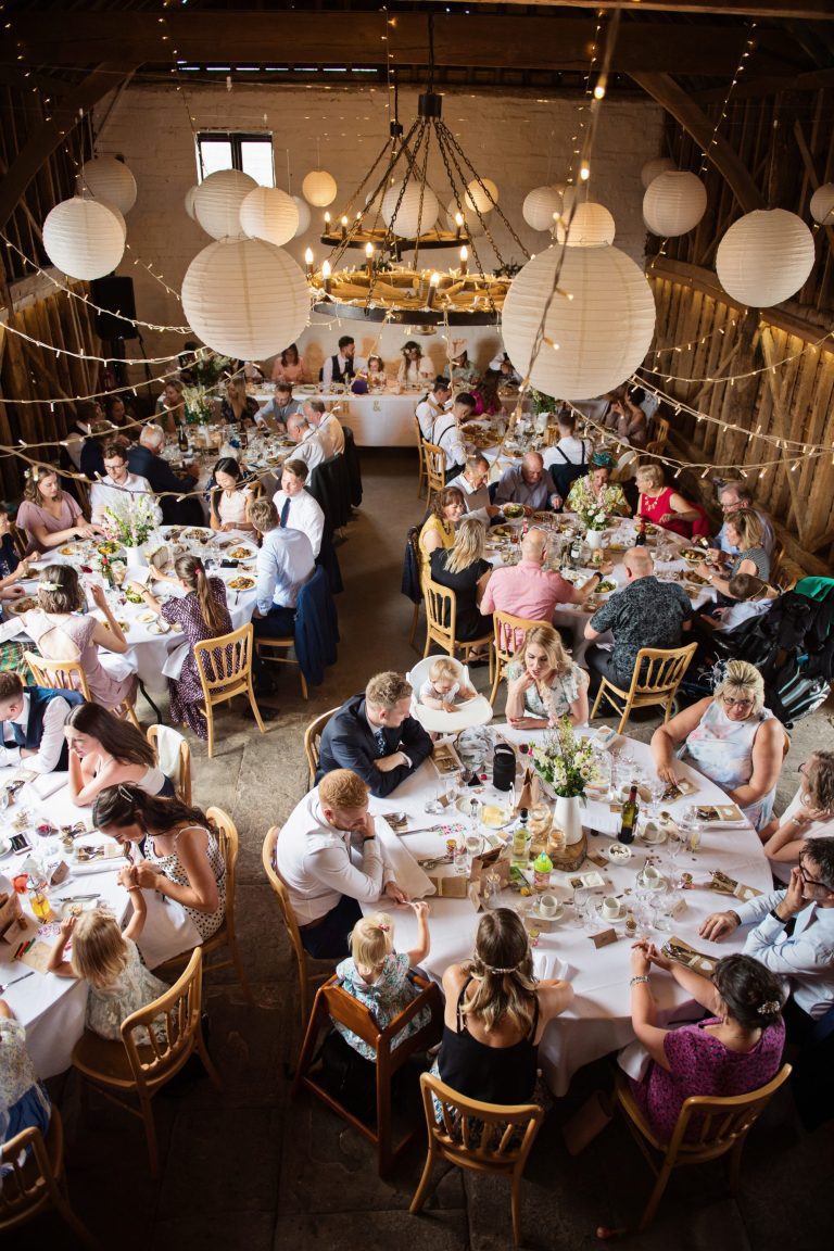 Portrait overview of Over Barn with wedding guests sitting waiting for their wedding food.