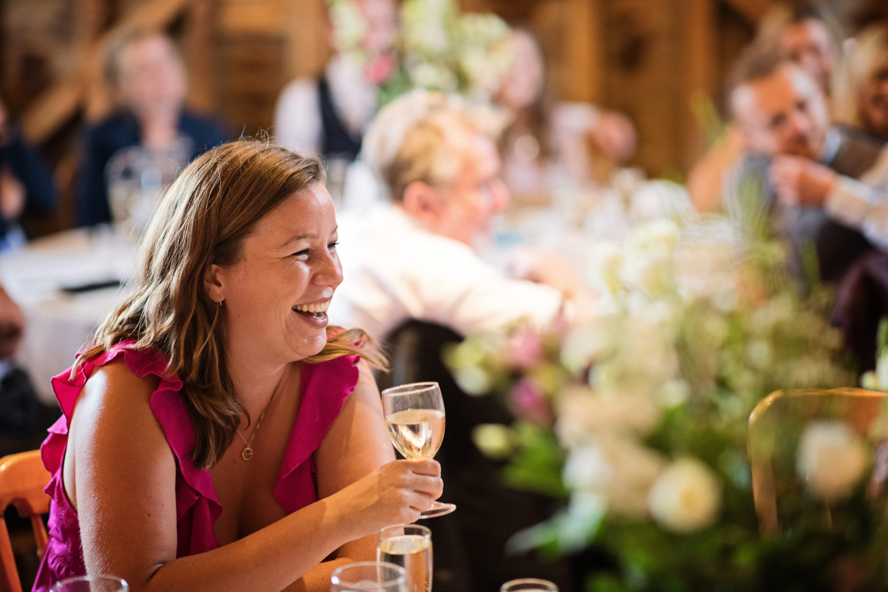 Candid photo of a wedding guest laughing at a wedding speech at Overbarn, Gloucester.