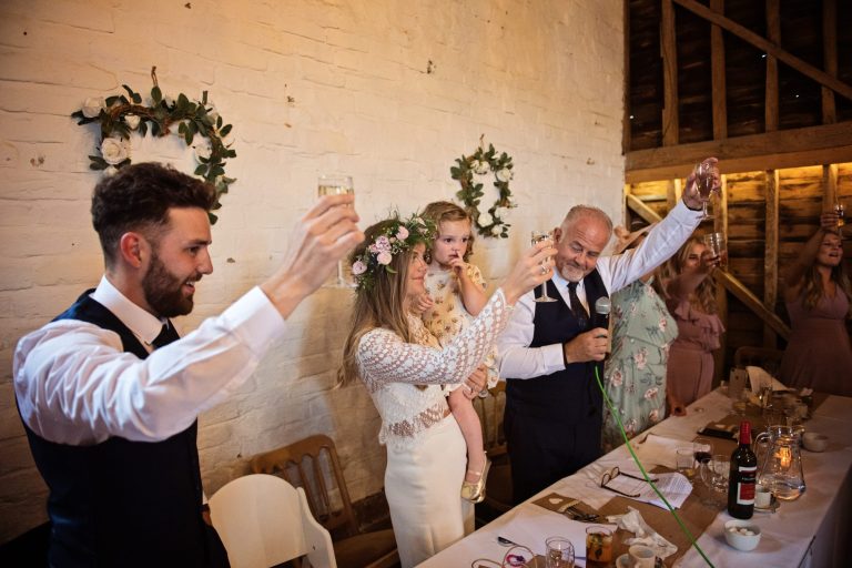 Top table at the wedding raise their glass at the end of a wedding speech.