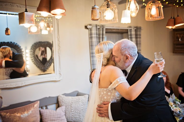 Father of the bride hugging his daughter (bride) for the first time when she is her wedding dress. In the bridal suite at Blackwell Grange. Emotional