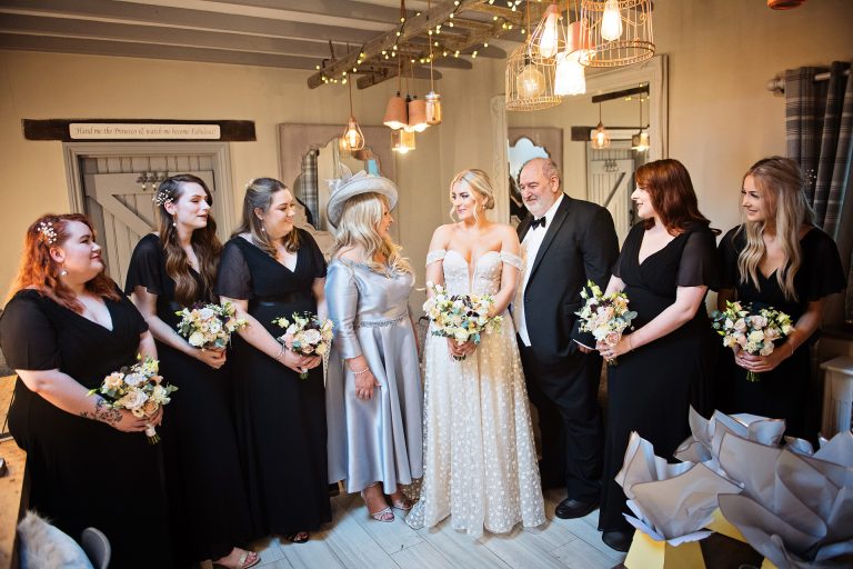 Bride, brides parents and bridesmaids take a moment together in the bridal suite at Blackwell Grange.