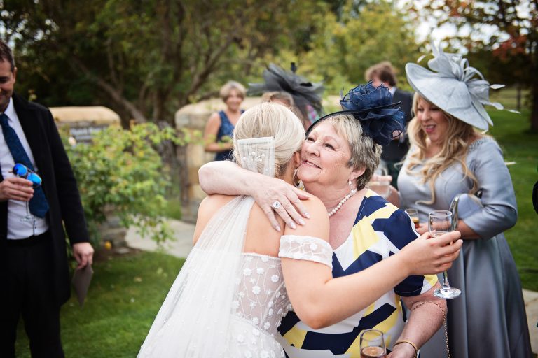Candid photo by Blooming Photography taken at Blackwell Grange. A bride being hugged by an auntie