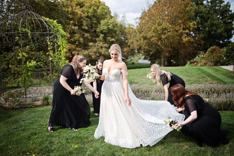 Elegant photo of the bridesmaids laying out the the brides wedding dress trail. Photo by Blooming Photography taken at Blackwell Grange, Warwickshire wedding.