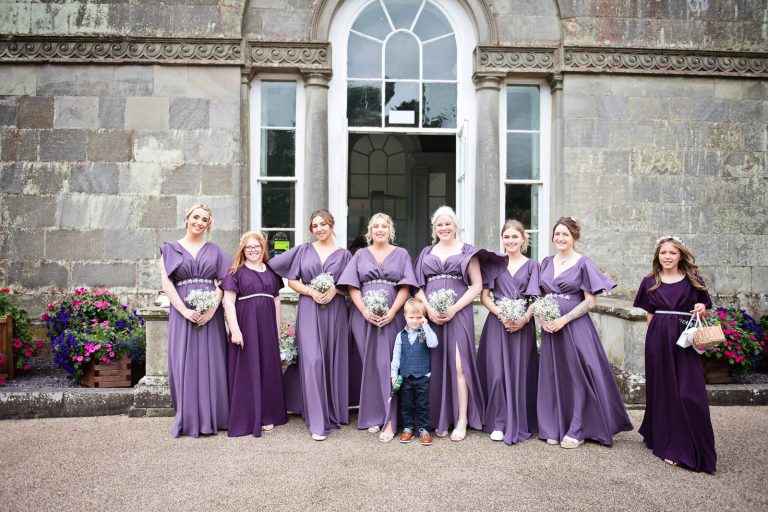 Bridesmaids aligned up alongside each other. Purple bridesmaids dresses.