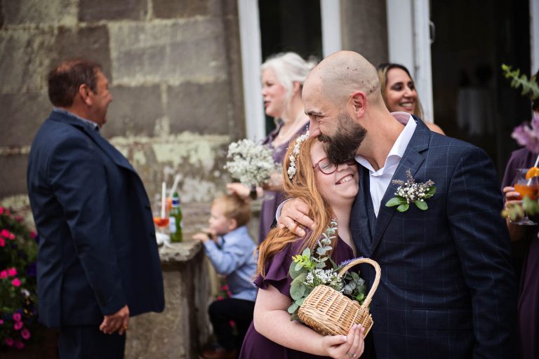 Photo of groom hugging a relative taken at a wedding.