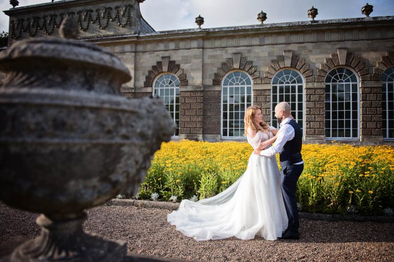 Natural wedding photograph of bride and groom hugging and smiling outside the Orangery.