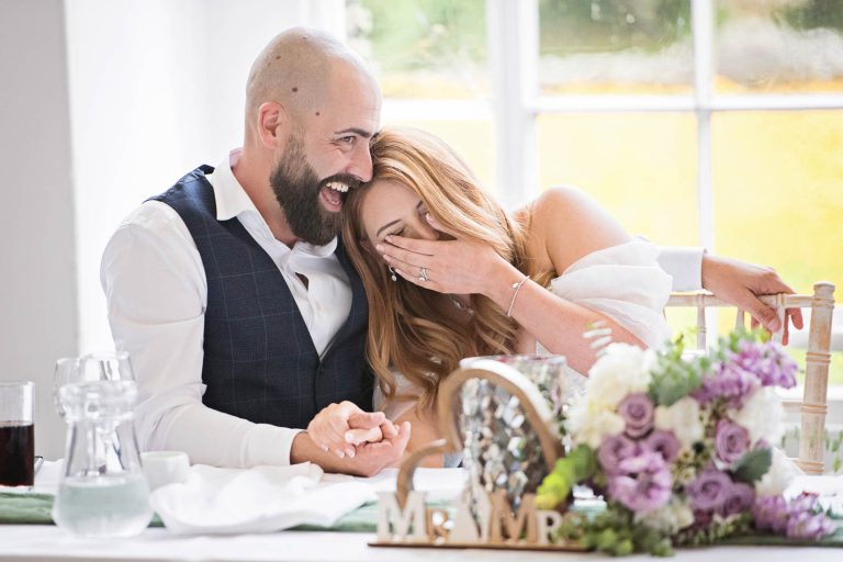 Natural image of the bride and groom laughing together taken during the wedding speeches at Margam Country Park.