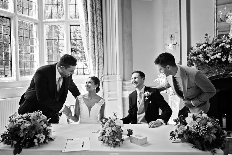 Bride and groom get congratulated by their witness'. Black and white photograph.