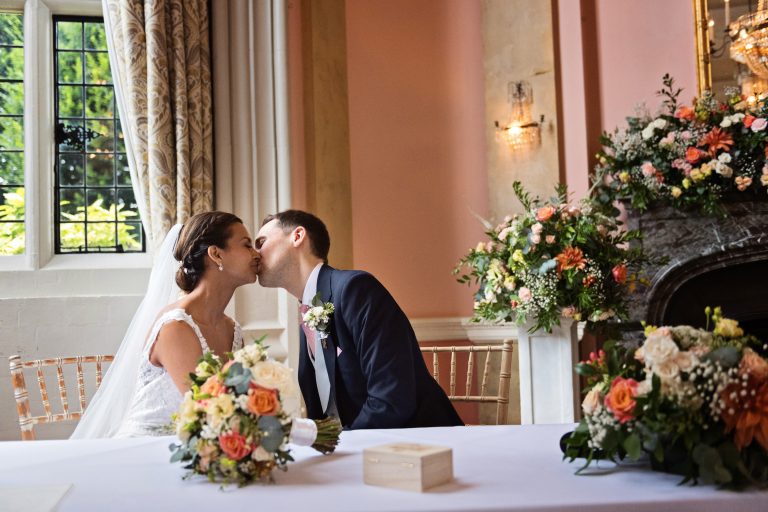 A bride and groom kiss after signing the marriage certificate.