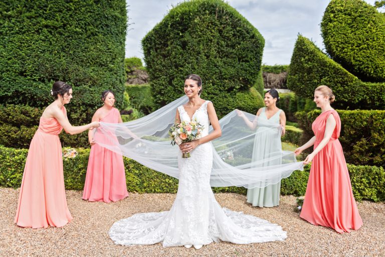 Bridesmaids layout the brides wedding veil. Elegant shot with the formal gardens at Danesfield House behind them.