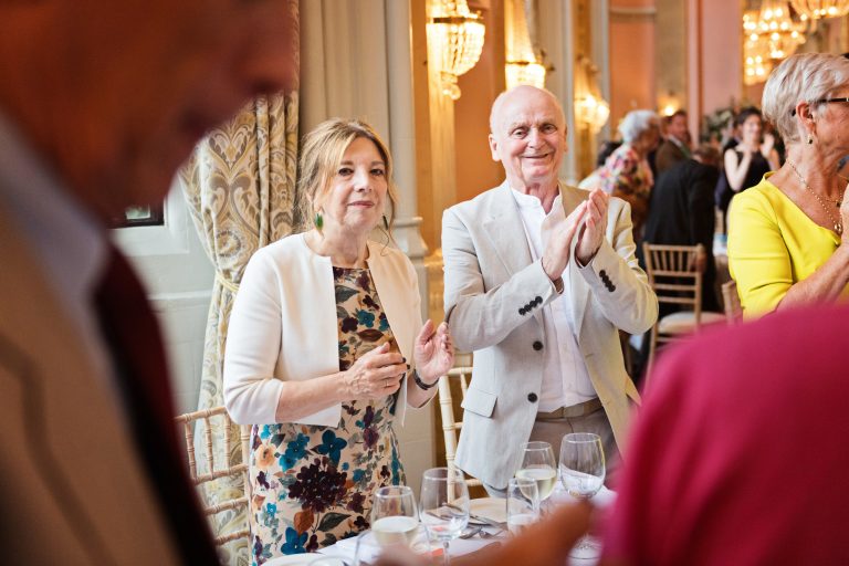Guests clapping in a candid photo taken as the bride and groom (not seen in picture) enter Danesfield House Ballroom.