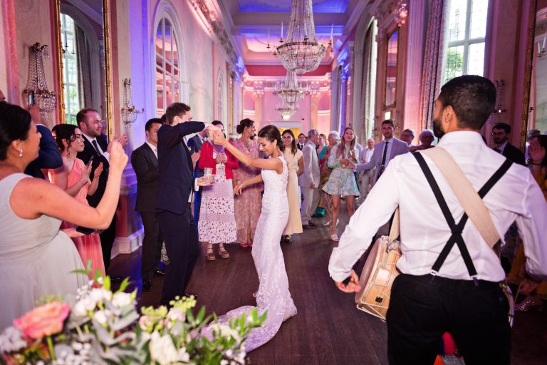 Bride and groom dance to the drumbeat of the Indian drummers. Photographed in the elegant Danesfield House Hotel and Spa Ballroom.