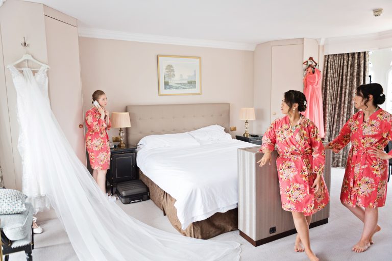 Bridesmaids getting the call to say you need to get ready by the hotel. Dress is laid out elegantly in between them.