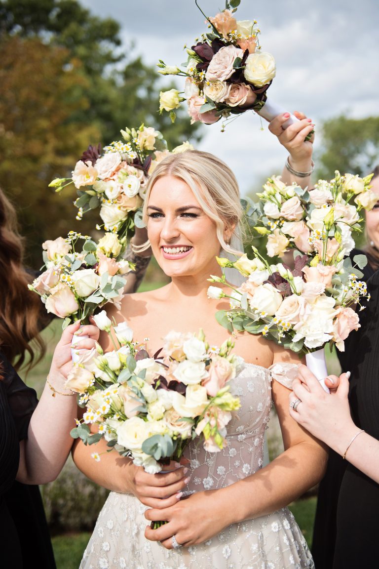 Bride smiling, surrounded by her bridesmaids flowers