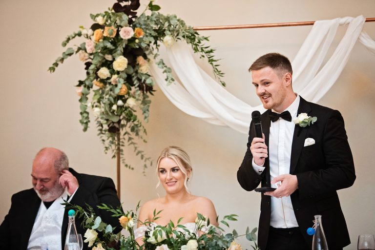 Groom delivering his speech. Bride and brides father behind the groom. Candid photo by Blooming Photography. Taken at Blackwell Grange, Warwickshire.