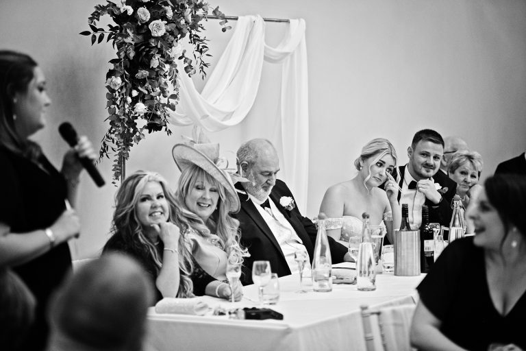 B&w image of the bride wiping her eye during the maid of honour speech. Candid photo by Blooming Photography. Taken at Blackwell Grange, Warwickshire.