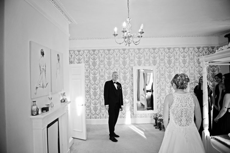 B&W photo of the brides father, seeing his daughter (aka the bride) for the first time in her wedding dress. Photo captured by Blooming Photography at Eastington Park
