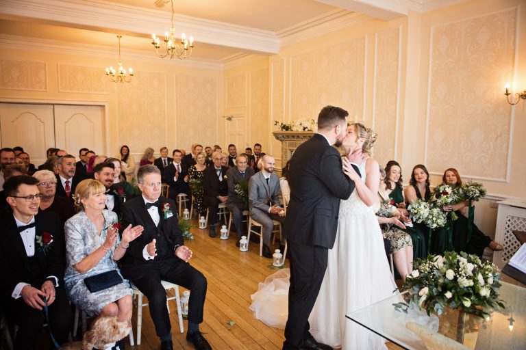 Bride and groom kiss as they are announced husband and wife at Eastington Park wedding venue. Photo by Blooming Photography