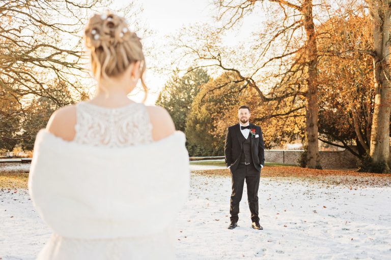 A winters scene, with gorgeous golden hour light with the groom facing his wife as they stand apart.