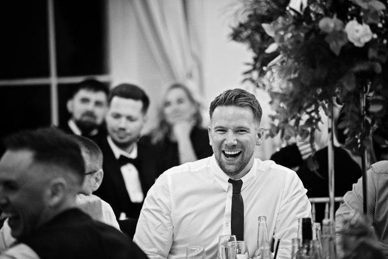 B&w photo of wedding guests smiling and laughing.