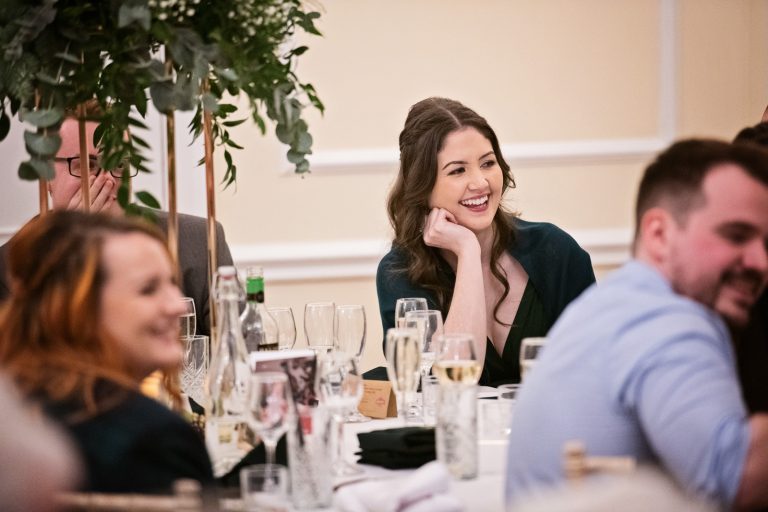 Guests smile at funny speeches. Photograph by Blooming Photography taken at Eastington Park at Christmas Wedding.