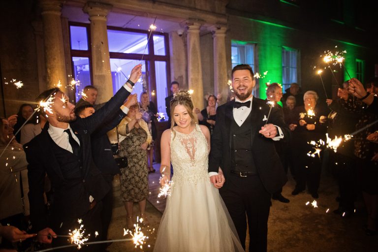 Bride and groom with their friends and family surrounding them outside with sparklers. Taken at Eastington Park at Christmas Wedding.