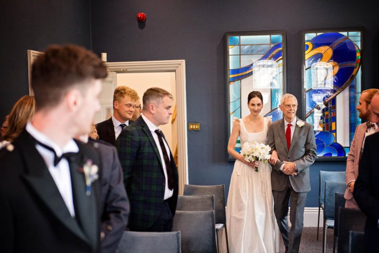 Bride walking down the isle at Winchester Registry Office Wedding, candid photo by Blooming Photography