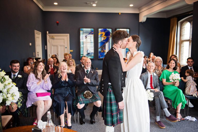 Ceiling the wedding ceremony with a kiss at Winchester registry office. Photo by Blooming Photography