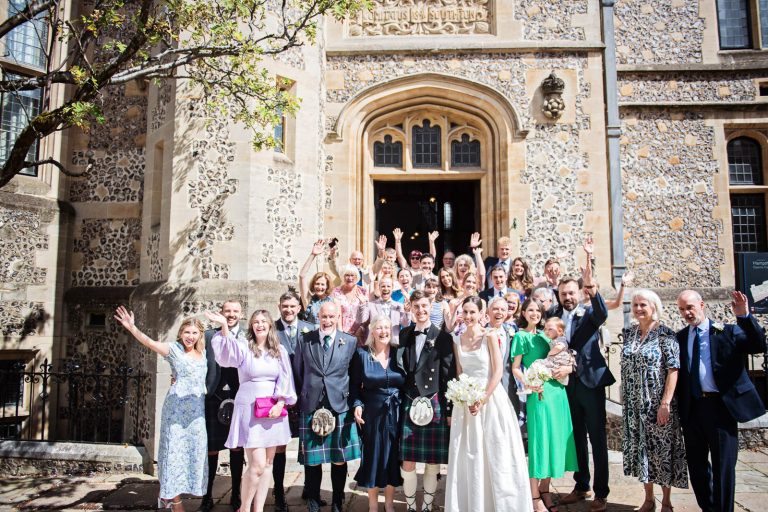 Fun group photo outside Winchester Registry Office in celebration after a wedding. Group photo by Blooming Photography