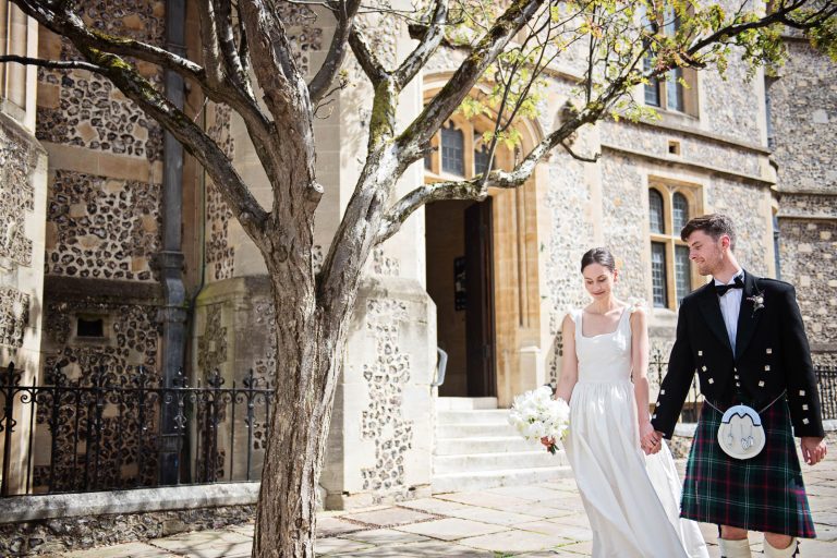 Candid wedding photo of bride and groom walking hand in hand outside Winchester Registry office photo by Blooming Photography.