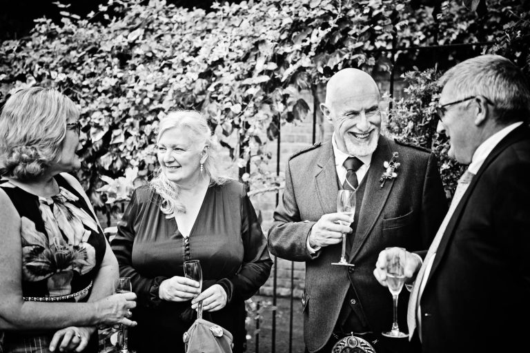 Candid wedding photo of guests talking at Hotel Du Vin Winchester, Black & white photo by Blooming Photography