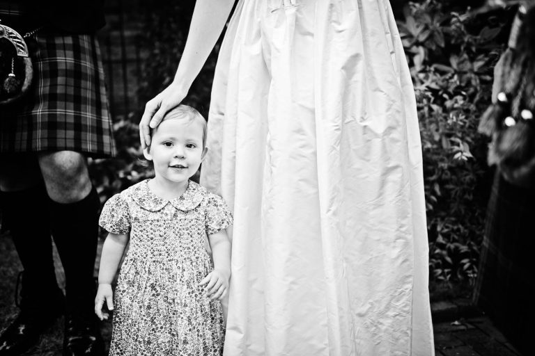 Black and white photo of flower girl and brides wedding dress, photo by Blooming Photography