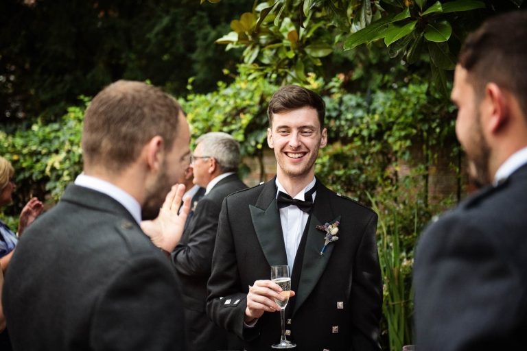 Candid wedding photo of groom talking to guests at Hotel Du Vin Winchester, photo by Blooming Photography