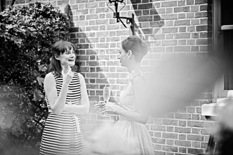 Natural wedding photo of a guest talking to bride at Hotel Du Vin Winchester, Black & white photo by Blooming Photography