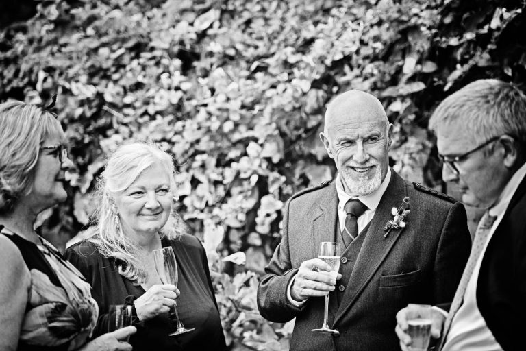 Candid wedding photo of guests talking to each other at Hotel Du Vin Winchester, Black & white photo by Blooming Photography