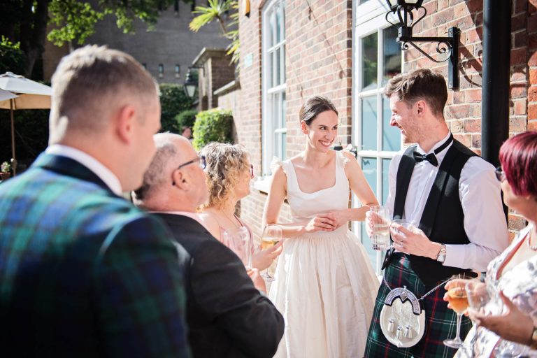 Candid wedding photo of guests talking to bride & groom at Hotel Du Vin Winchester, photo by Blooming Photography