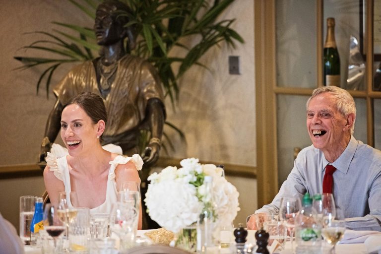 Bride and father of bride laughing at the wedding speech.