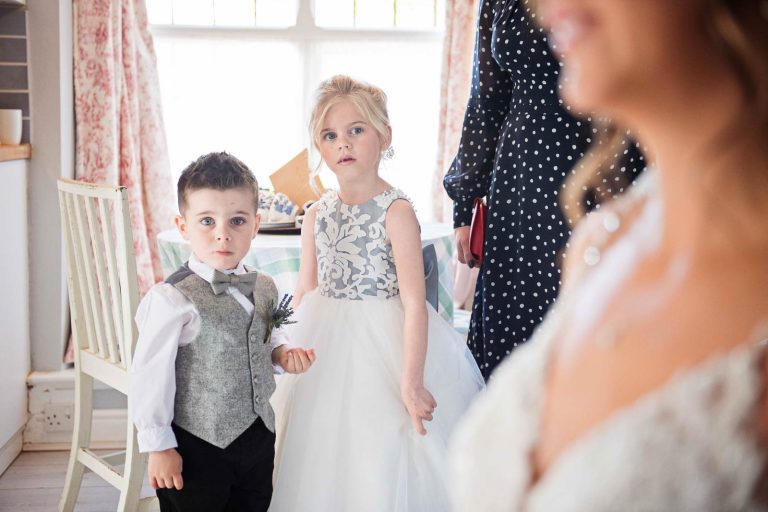 Flowergirl and pageboy look at the bride as she gets ready.