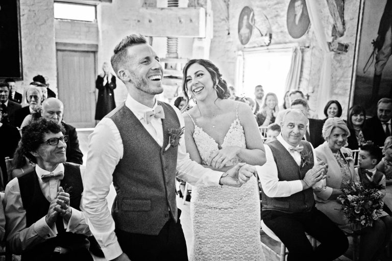 Documentary photo during a wedding ceremony at Owlpen Manor. Bride and groom laughing.