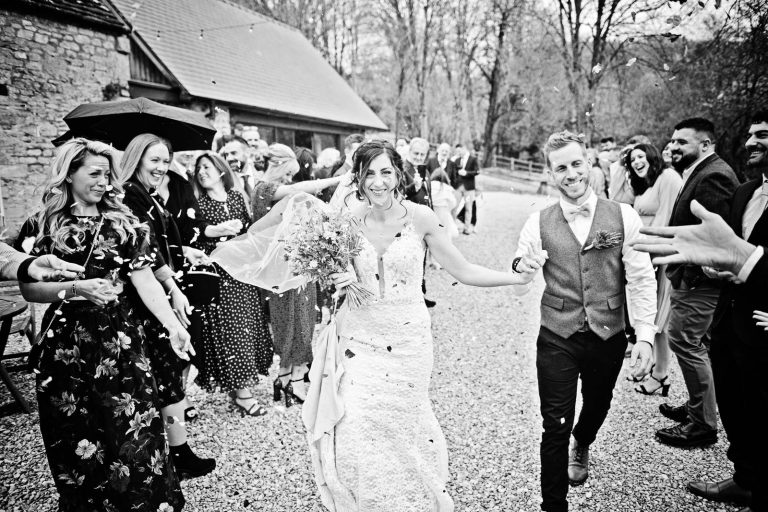 Storytelling image of bride and groom having a confetti shower during their wedding at Owlpen Manor.