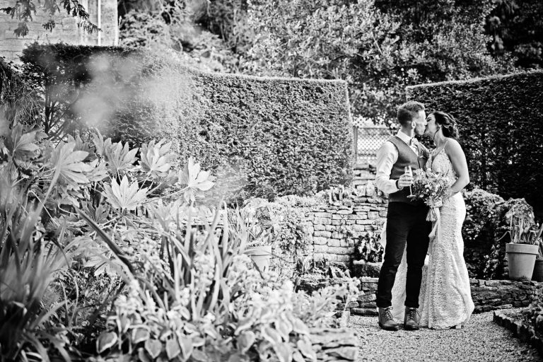 B&W photo of the bride and groom kissing in the grounds at Owlpen Manor.