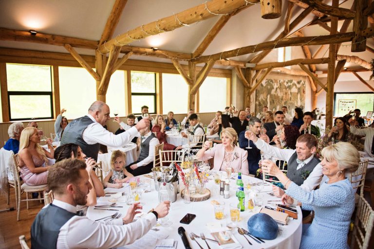 Candid photo of wedding guests raising their glasses during speeches at Owlpen Manor