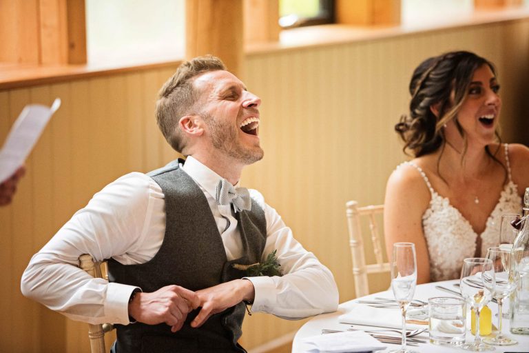 Candid photo of groom laughing during the speeches.