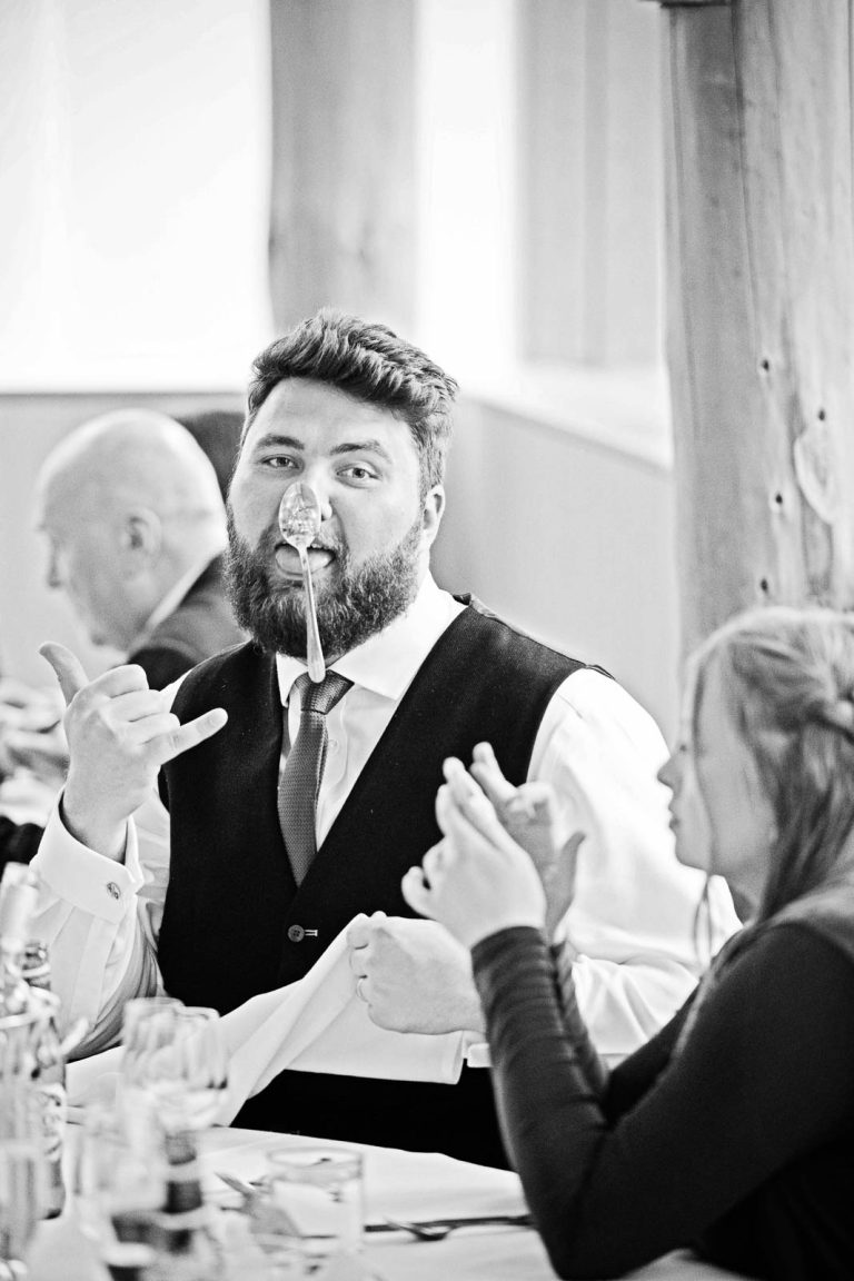 Wedding guest has a spoon balanced on his nose.