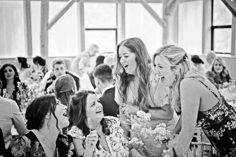 Candid photo of guests laughing during wedding breakfast. B&W image.