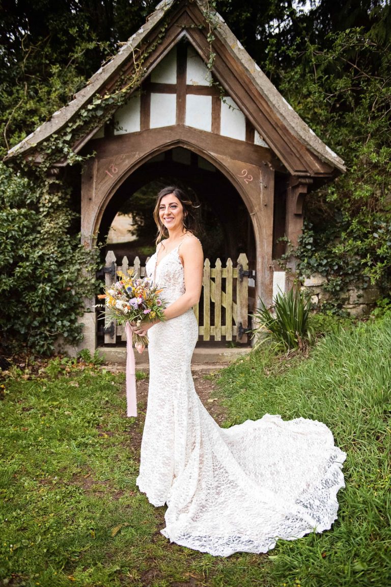 Bride holding her flowers in front of an old arch and gate,