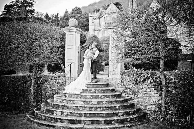 B&W photo of bride and groom on the steps in the grounds at Owlpen Manor.
