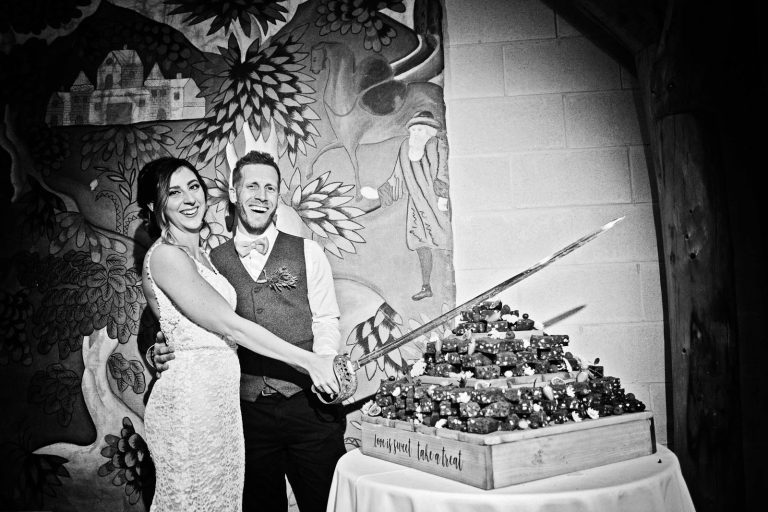Bride and groom cut cake with a very long sword.