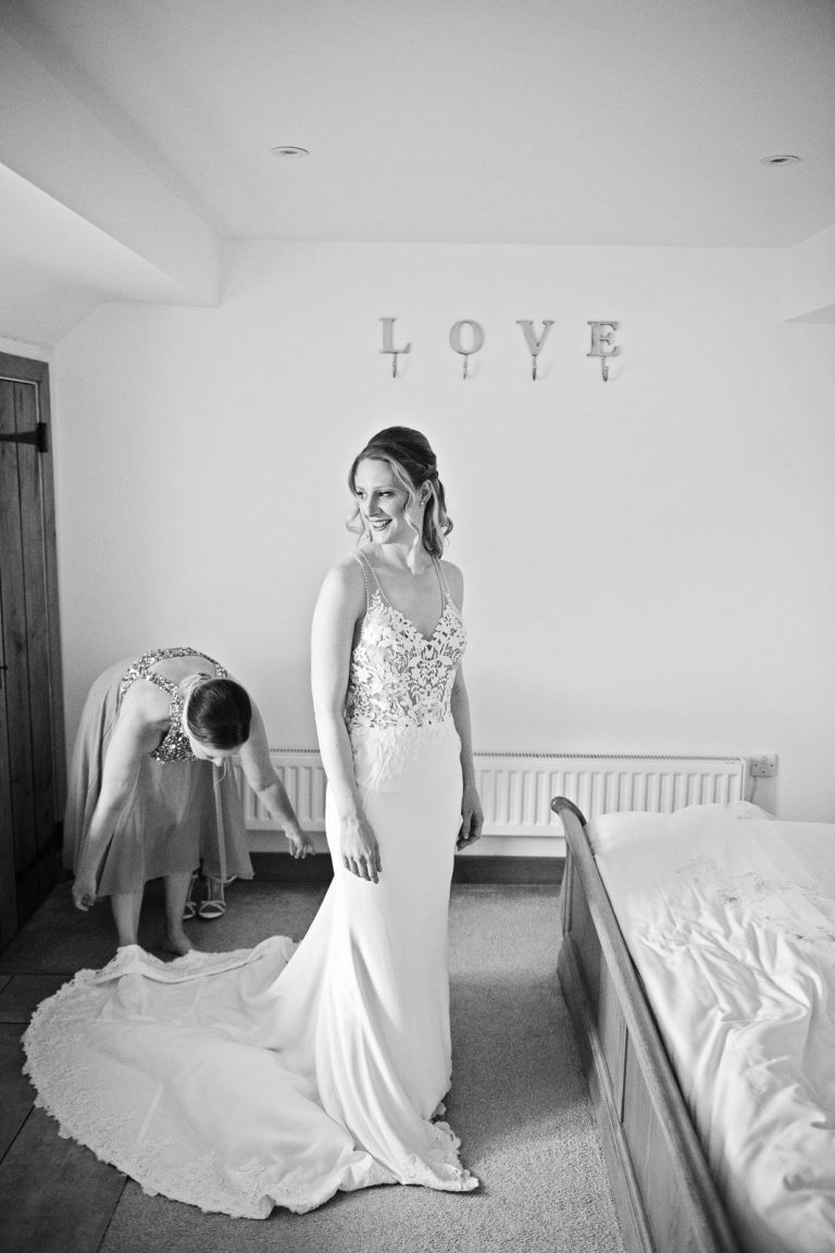 B&W photo of bride getting her wedding dress on.