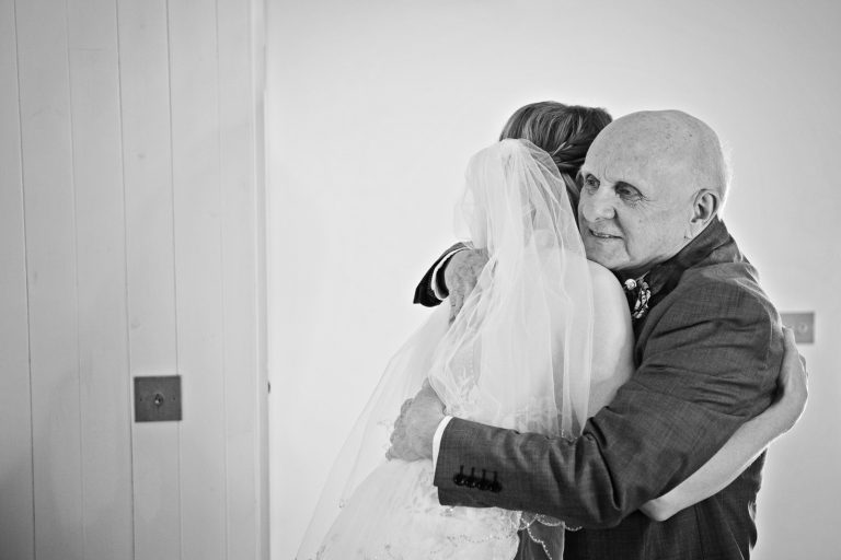 B&W natural photo of father of the bride hugging his daughter.